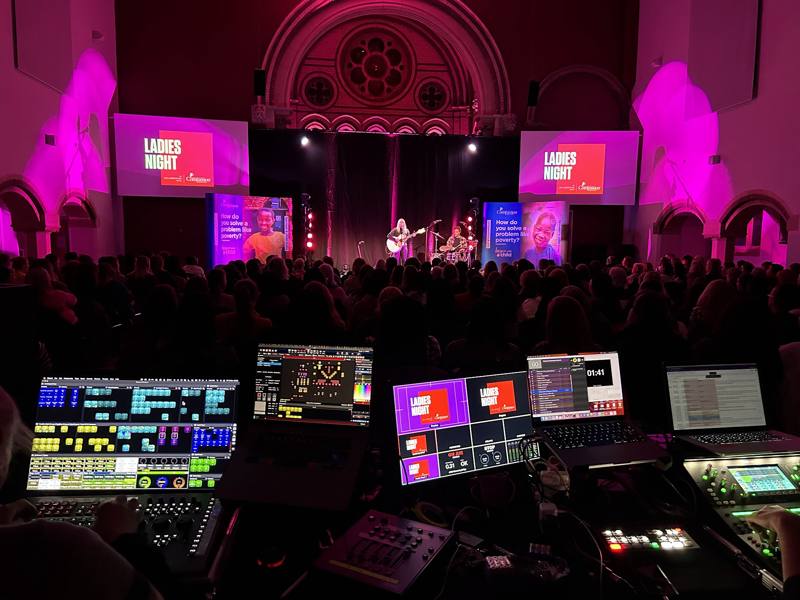 Ladies Night tour: the view from the production desk across a packed audience to a singer with a guitar on a pink-lit stage